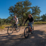 a couple riding mountain bikes on a ranch trail