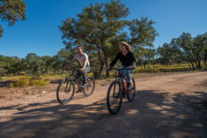 a couple riding mountain bikes on a ranch trail