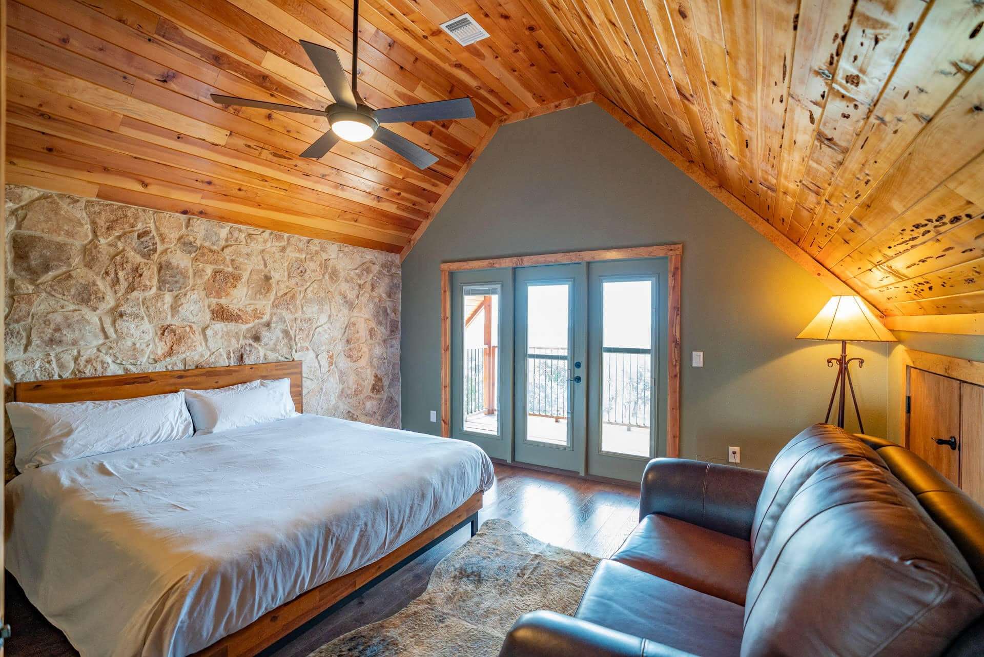 Artemis Cottage primary bedroom with stone wall and balcony doors