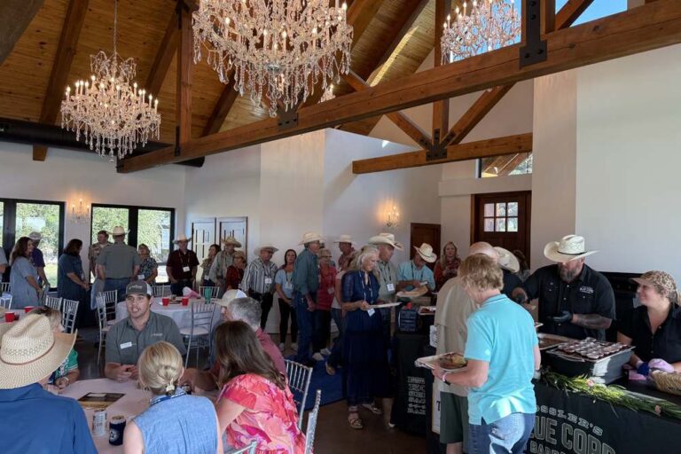 Corporate group mingling beneath chandeliers during a catered event at Artemis Ranch & Retreat