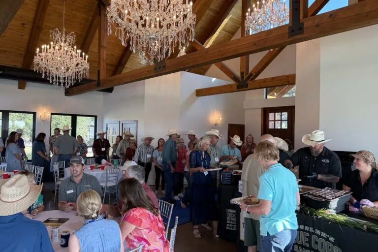 Corporate group mingling beneath chandeliers during a catered event at Artemis Ranch & Retreat