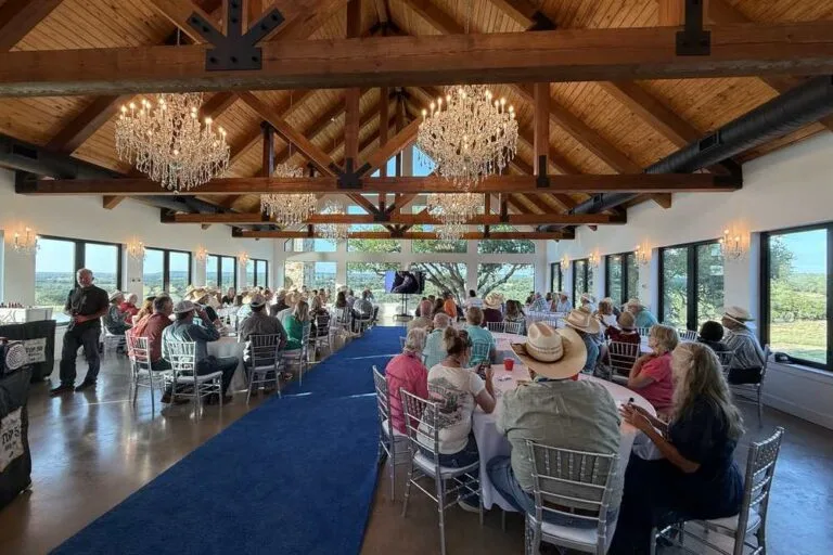 Corporate retreat guests seated at tables in the vaulted-ceiling hall at Artemis Ranch & Retreat